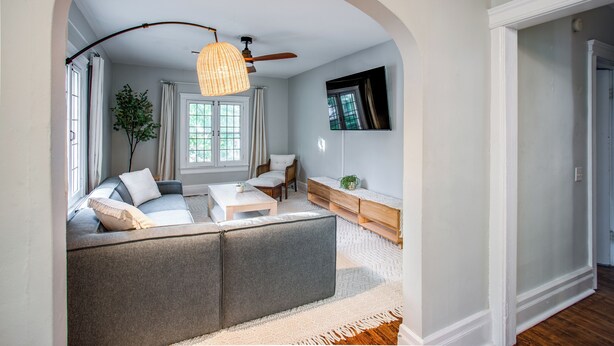 A living room with a grey sofa, a coffee table, a wooden side table, and a hanging light fixture.