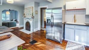 A modern kitchen with a stainless steel refrigerator, white cabinets, and a fireplace.