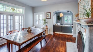 A dining area with a wooden table and benches, a white sofa, and a fireplace.