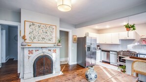A modern kitchen with white cabinets, a stainless steel refrigerator, and a fireplace with a decorative vase.