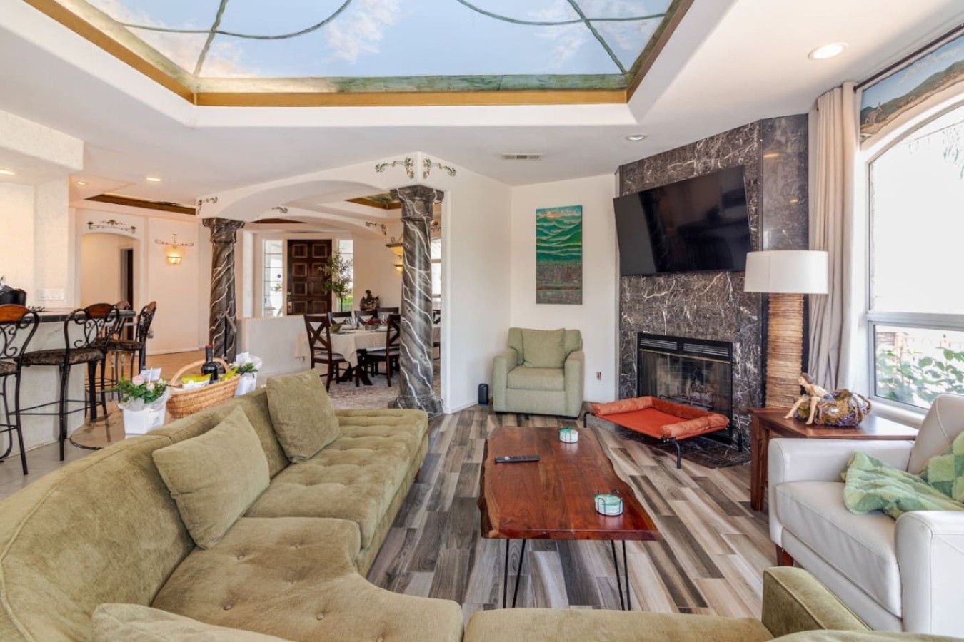 A modern living room with a sectional sofa, a fireplace, and a dining area in the background.
