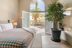 A bedroom with a bed, a large potted plant, and a view of the outside. - Mountain View Oasis  AC, Pool, Pet & Family Friendly (Hemet)