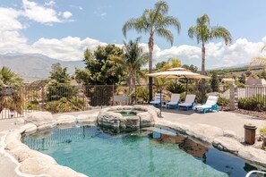 A swimming pool with lounge chairs and palm trees, surrounded by a fence. - Mountain View Oasis  AC, Pool, Pet & Family Friendly (Hemet)