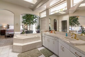A modern bathroom with a large bathtub, dual sinks, and a large mirror. - Mountain View Oasis  AC, Pool, Pet & Family Friendly (Hemet)