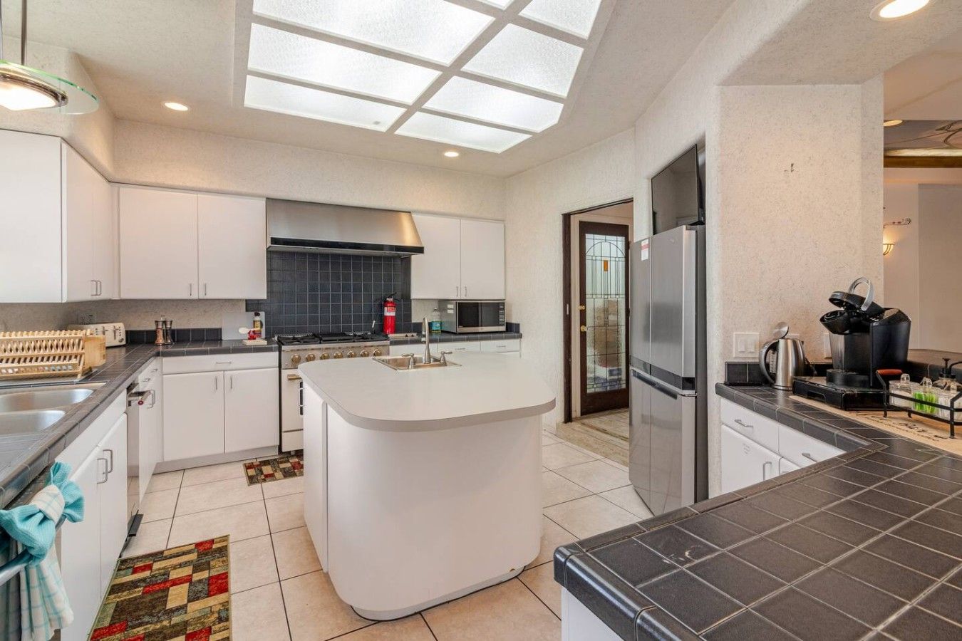 A modern kitchen with a central island, a stove, microwave, and a refrigerator.