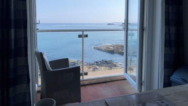 Ein Balkon mit Meerblick, ein Stuhl und ein Tisch.