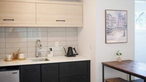 A modern kitchen with a white countertop, black cabinets, and a small dining table. - Seattle's Ballard new studio (Seattle)