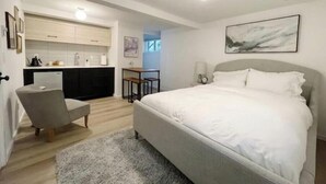 A modern bedroom with a large bed, a desk, and a kitchenette. - Seattle's Ballard new studio (Seattle)