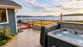 Un jacuzzi en una terraza con vistas a un lago y una valla de madera.