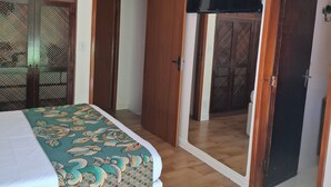 A bedroom with a bed, a TV mounted on the wall, and a wooden door.