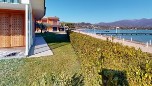 Un edificio moderno con balcón, un césped bien cuidado y vistas a un lago con barcos.