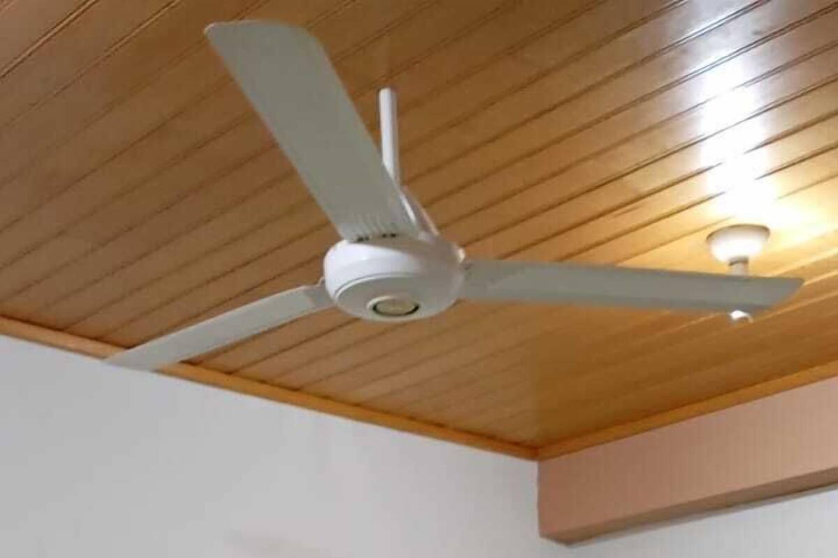 A room with two beds, a ceiling fan, and a light fixture.