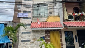 A multi-story building with a tiled roof and a yellow door. - Apart hotel Emanuel & Cavita  (Iquitos)