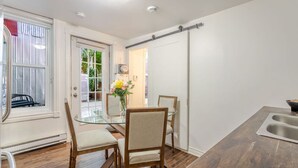 A modern kitchen with a wooden table, two chairs, a glass-top table, and a stainless steel sink. - The Metro Stay – Vibrant 3BR in Gay Village (Montréal)