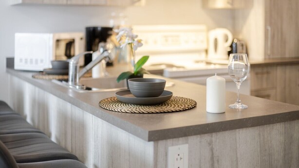 A modern kitchen with a built-in microwave, a coffee maker, and a sink. - The Prestige 3BR| Griffintown Views (Montréal)