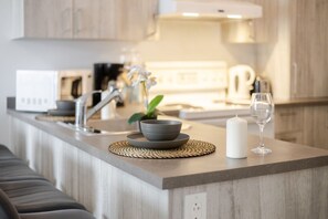 A modern kitchen with a built-in microwave, a coffee maker, and a sink. - The Prestige 3BR| Griffintown Views (Montréal)
