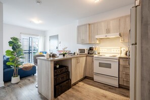 Una cocina compacta con armarios de madera, horno empotrado y microondas.