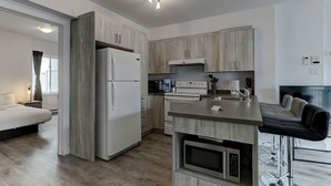 Eine kompakte Küche mit Kühlschrank, Mikrowelle, Herd und Spüle.