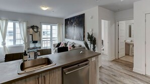 Eine moderne Küche mit Kochinsel, Essbereich mit Sofa und Blick auf die Stadt durch große Fenster.