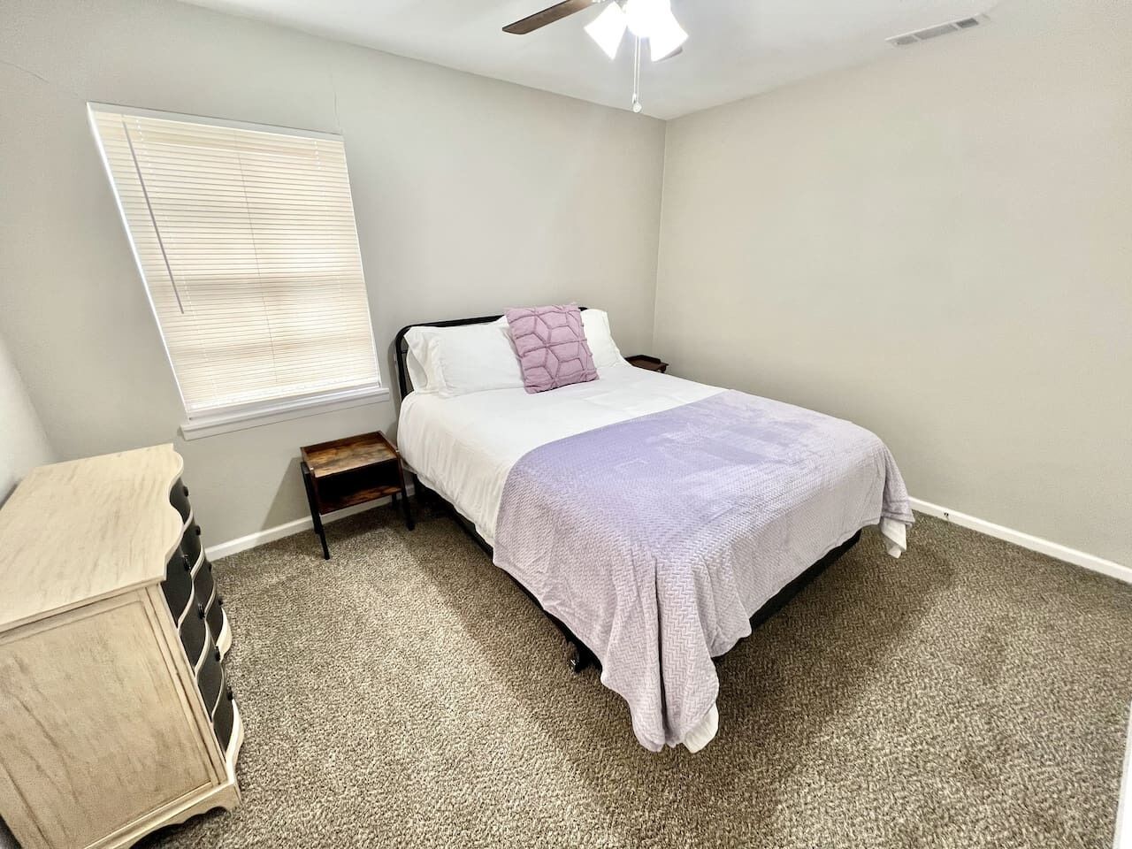 Un dormitorio con cama, mesita de noche, cómoda y ventilador de techo.