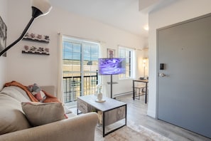 A living room with a sofa, a coffee table, a TV, and a balcony with a view. - Bright & Beautiful 3 Bedroom in Griffintown (Montréal)