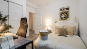 A bedroom with a bed, a chair, a lamp, a painting, and a plant. - Chic and Spacious 3 Bedrooms in Griffintown (Montréal)