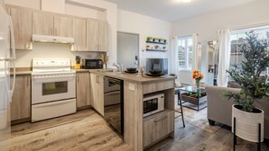 A modern kitchen with wooden cabinets, a built-in oven, microwave, and dishwasher. - Chic and Spacious 3 Bedrooms in Griffintown (Montréal)