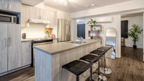 A modern kitchen with a central island, stainless steel appliances, and a bar stool seating area. - Amazing 4 Bedroom Unit in Downtown (Montréal)