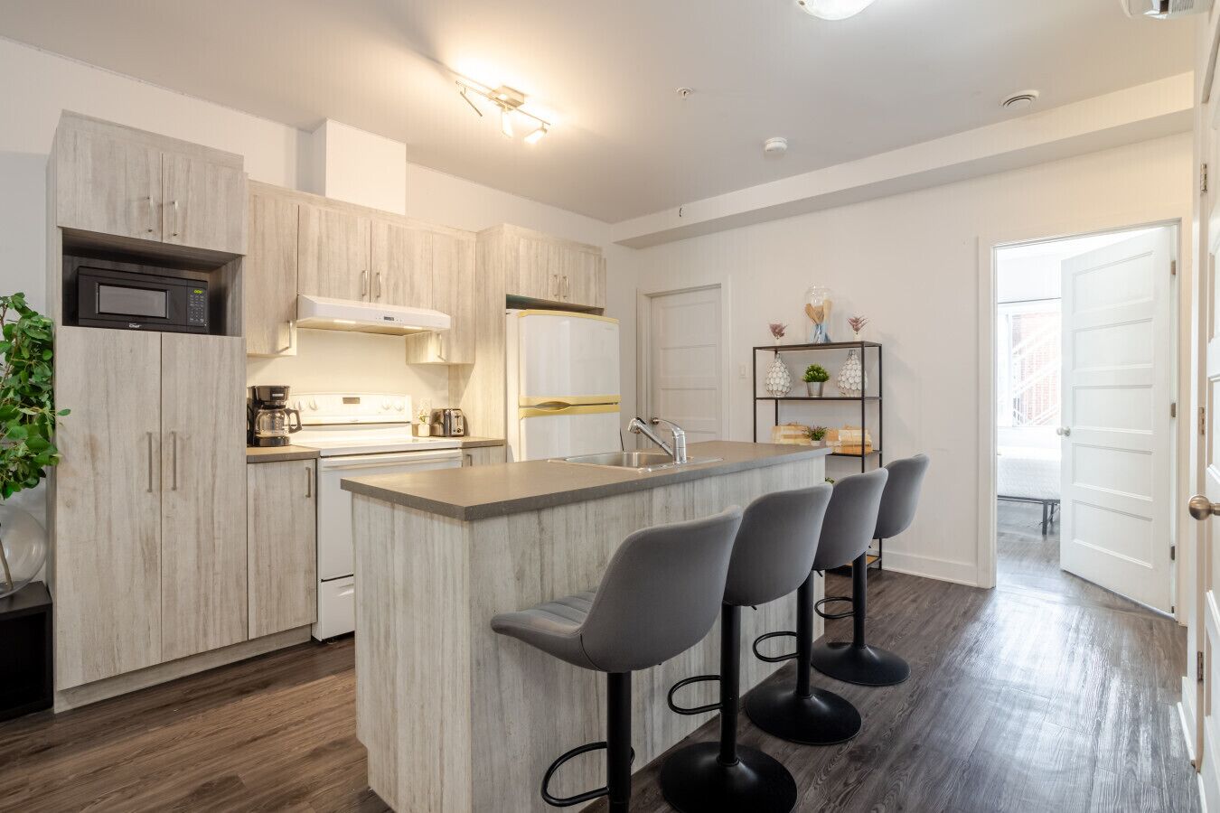 A modern kitchen with a central island, bar stools, and a built-in microwave.