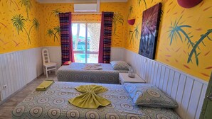 A room with two beds, a chair, and a window with curtains.