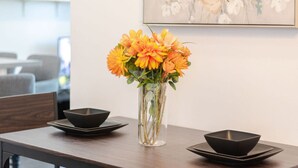 Une table à manger avec deux bols noirs et un vase rempli de fleurs oranges.