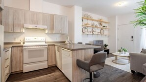 Une cuisine moderne avec des meubles en bois, une cuisinière blanche et un lave-vaisselle encastré. On y trouve également un coin repas avec une table ronde et deux chaises.