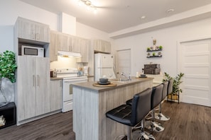 A modern kitchen with a central island, bar stools, and a built-in oven.