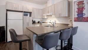 Una cocina moderna con una isla central, taburetes de bar, un microondas, una estufa y un fregadero.