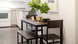 Un comedor con una mesa dispuesta para dos, una planta en maceta, velas y un cuadro en la pared.