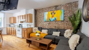 Ein modernes Wohnzimmer mit grauem Sofa, Couchtisch aus Holz und einem Gemälde an der Backsteinwand.