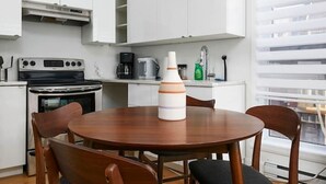 Una cocina moderna con armarios blancos, una mesa redonda de madera y cuatro sillas.