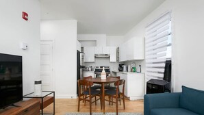 Un apartamento moderno con sala de estar, comedor, kitchenette y un televisor sobre un soporte de madera.