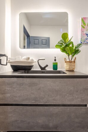 A bathroom with a modern sink, a mirror, and a potted plant. - Prime Location | Charming 4BR in Downtown MTL (Montréal)