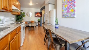 A modern kitchen with wooden cabinets, a dining table with chairs, a refrigerator, and a potted plant. - Prime Location | Charming 4BR in Downtown MTL (Montréal)