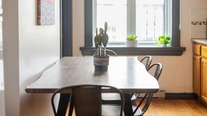 A dining area with a table, chairs, a cactus sculpture, and a window with plants. - Prime Location | Charming 4BR in Downtown MTL (Montréal)