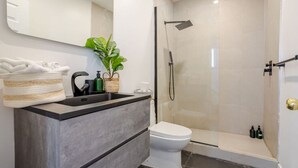 A modern bathroom with a grey vanity, white sink, and a glass-enclosed shower. - Prime Location | Gorgeous 4BR Downtown MTL (Montréal)