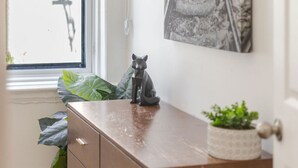 A wooden dresser with drawers, a small potted plant, and a cat figurine on top. - Prime Location | Gorgeous 4BR Downtown MTL (Montréal)