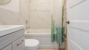 A bathroom with a bathtub, toilet, and a shower curtain.