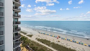 Un hôtel situé en bord de mer, doté de nombreux balcons offrant une vue sur l’océan.