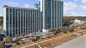 Un grand hôtel à plusieurs étages, doté d’une piscine et offrant une vue sur la plage.