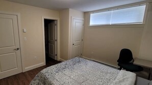 Quarto com cama, uma cadeira e janela.