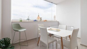 Un espace repas moderne avec une grande fenêtre, une table blanche et des chaises.