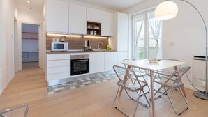 Une cuisine moderne avec des meubles blancs, un four à micro-ondes, une machine à café et un coin repas comprenant une table et des chaises.