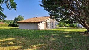 A single-story house with a tiled roof, a garage, and a lawn.